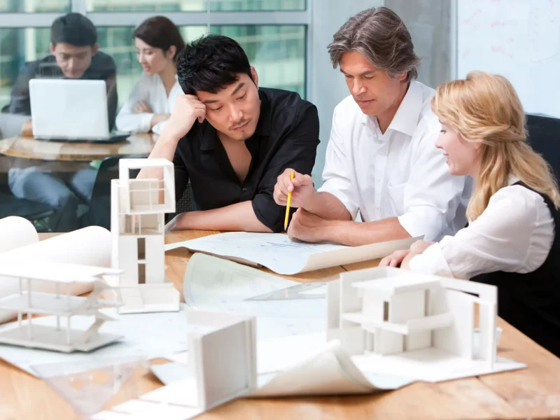 Chinese and western architects studying a blueprint